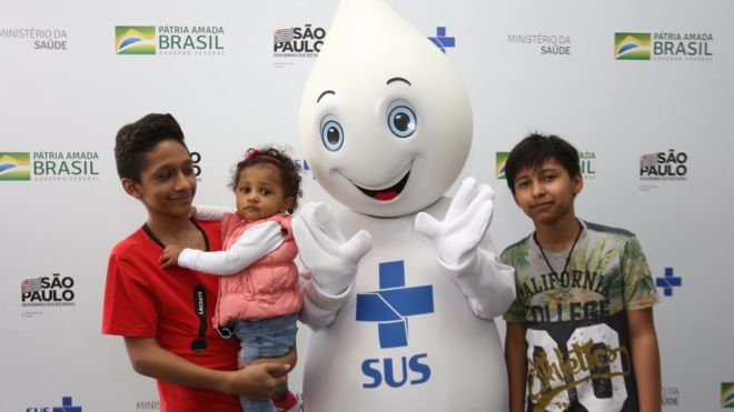 Crianças posando para foto com o Zé Gotinha