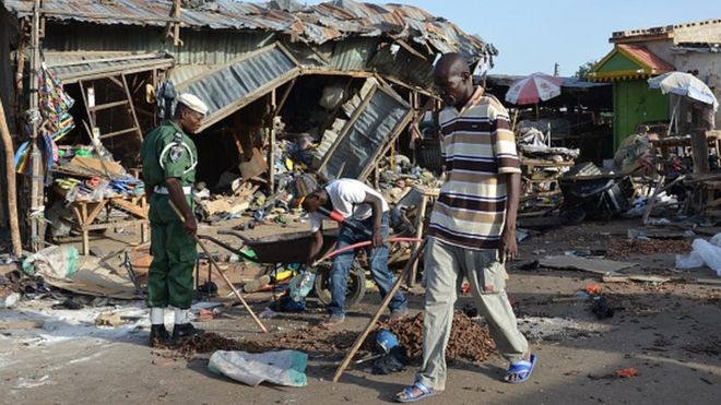 Мужчина проходит мимо места взрыва после того, как по меньшей мере 20 человек были убиты, когда молодая террористка-смертница взорвала ее взрывчатку на автобусной станции в Майдугури, северо-восточная Нигерия, 22 июня 2015 года в нападении, в котором, вероятно, обвиняют Боко. Харам