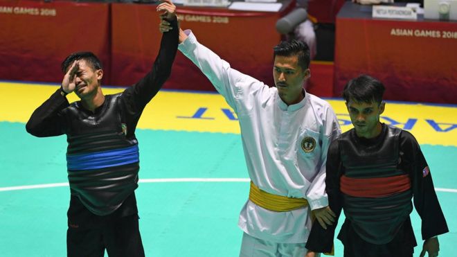 Pesilat Indonesia Abdul Malik (kiri) menangis usai dinyatakan menang atas pesilat Malaysia Muhammad Faizul M Nasir (kanan) dan meraih medali emas dalam babak final Kelas B Putra Asian Games 2018 di Padepokan Pencak Silat Taman Mini Indonesia Indah (TMII), Jakarta, Senin (27/8).