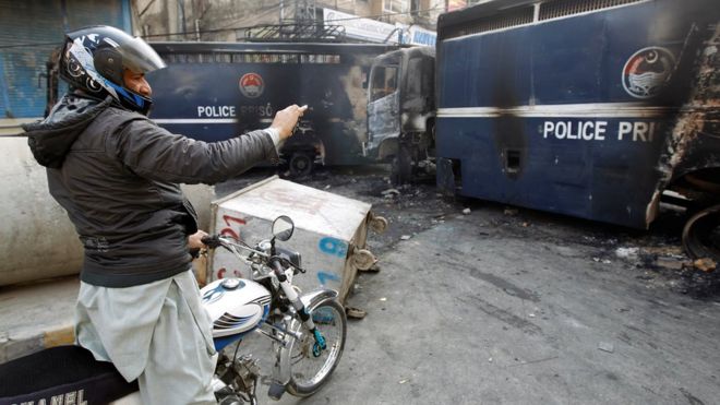 Мужчина в Исламабаде фотографирует сгоревшие полицейские машины
