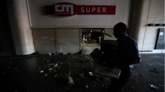 Сотрудник магазина помогает убирать территорию после того, как магазин был разграблен во время продолжающегося отключения электроэнергии в Каракасе, Венесуэла, 10 марта 2019 года.