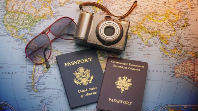 Dos pasaportes, unas gafas y una cámara sobre un mapa mundi.