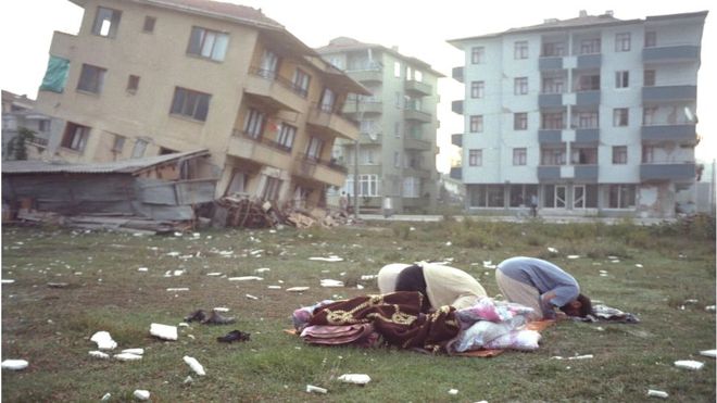 Unos hombres rezan frente a unos edificios destruidos por el terremoto de Izmit de 1999.