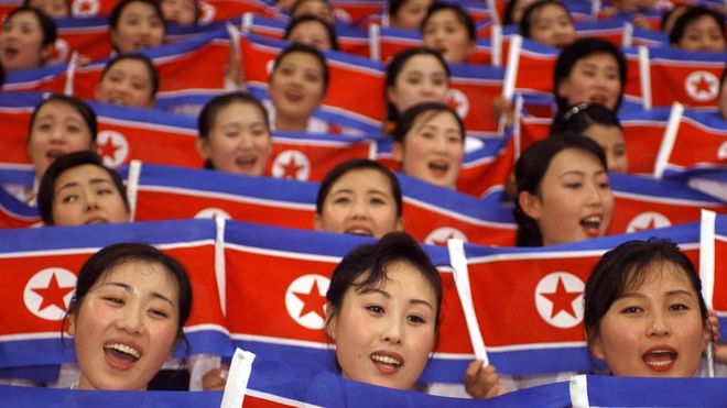 Члены северокорейской команды поддержки развевают свои национальные флаги во время церемонии открытия Всемирных студенческих игр в Тэгу 21 августа 2003 года.
