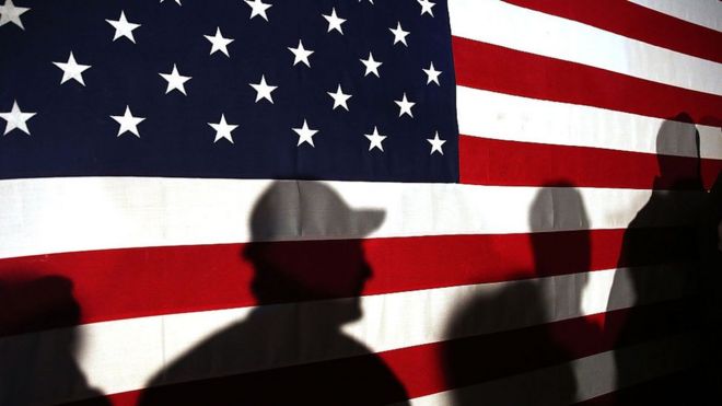 Workers silhouetted against the US flag