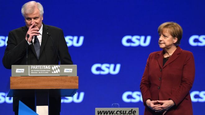 Хорст Зеехофер выступает на конгрессе CSU 20 ноября, а канцлер Ангела Меркель стоит на его стороне на сцене.