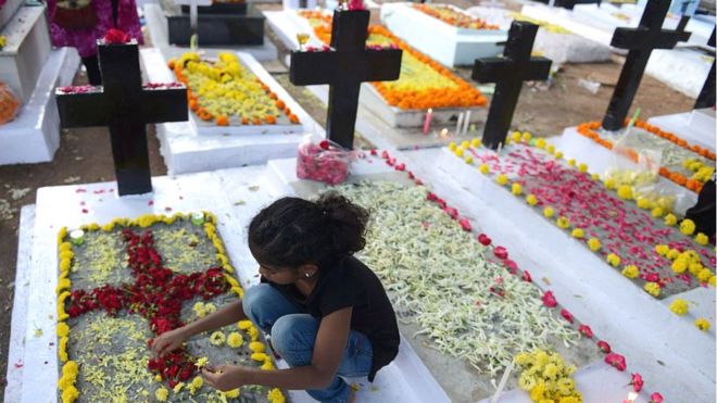 Индийская христианская девушка украшает могилы умерших членов семьи на католическом кладбище во время Дня всех душ в Хайдарабаде