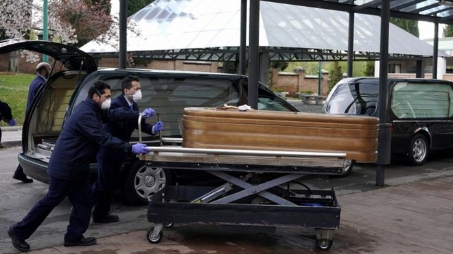Employees of a mortuary enter the crematorium of La Almudena cemetery with a coffin of a person who died of coronavirus disease in Madrid, March 23, 2020