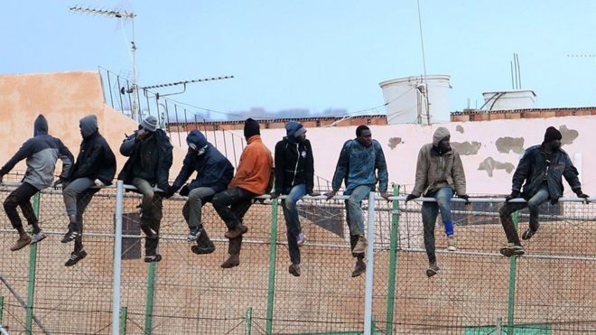 Мигранты сидят на пограничной ограде, отделяющей Марокко от испанского анклава Мелилья, 19 февраля 15