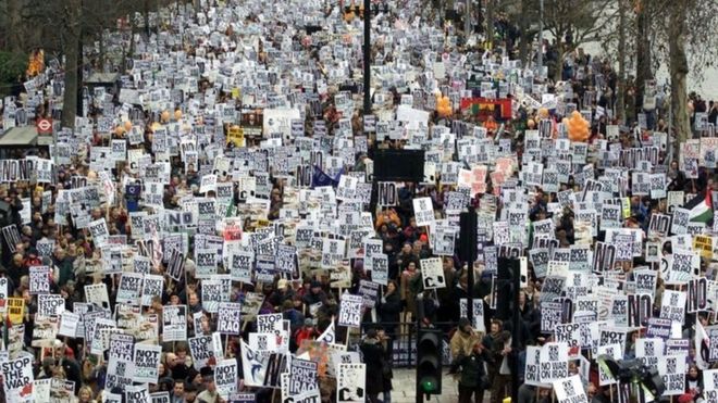 Протестующие идут по набережной в оппозиции к войне в Ираке в марте 2003 года