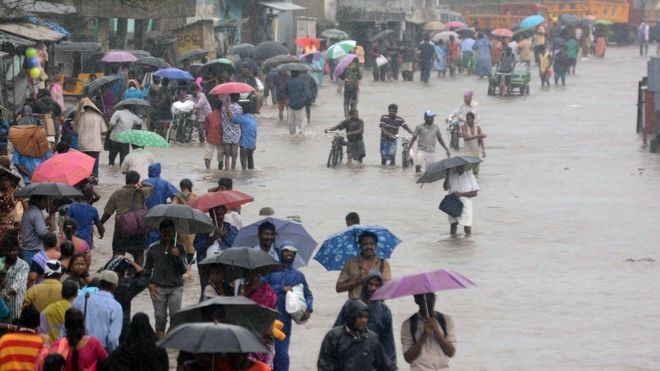 Индийцы пробиваются на затопленную улицу в Ченнаи 9 ноября 2015 года после проливного дождя из-за приближающейся циклонической системы у побережья. Индийские метеорологические власти выпустили предупреждение о циклоне для побережья Бенгальского залива в штате Тамилнад.