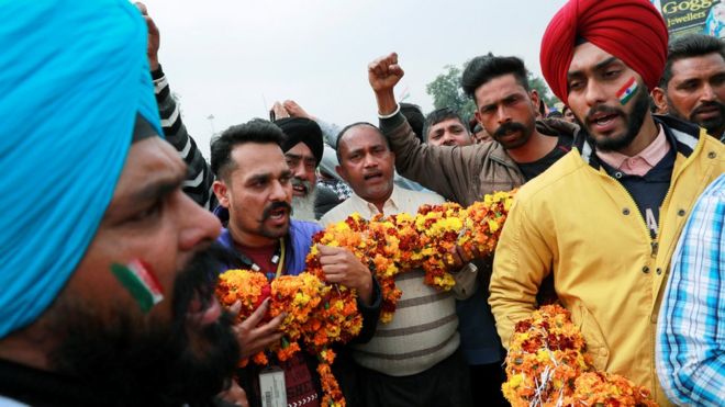 Люди держат в руках гирлянду, выкрикивая патриотические лозунги перед прибытием пилота ВВС Индии, который был захвачен Пакистаном в среду около границы Вага, на окраине северного города Амритсар, Индия, 1 марта 2019 года
