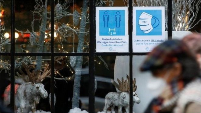 People pass by a restaurant window displaying coronavirus disease (COVID-19) safety measures,