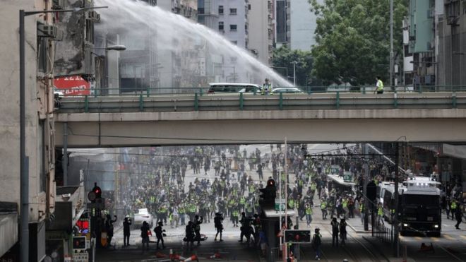 Полицейские водометные машины распыляют воду для разгона протестующих во время митинга против введения в действие нового закона о национальной безопасности в Козуэй-Бэй, Гонконг, Китай, 24 мая 2020 года