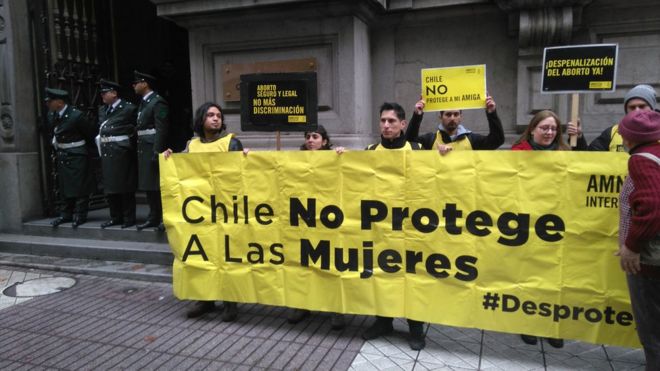 Активисты держат плакат с надписью: «Чили не защищает женщин».