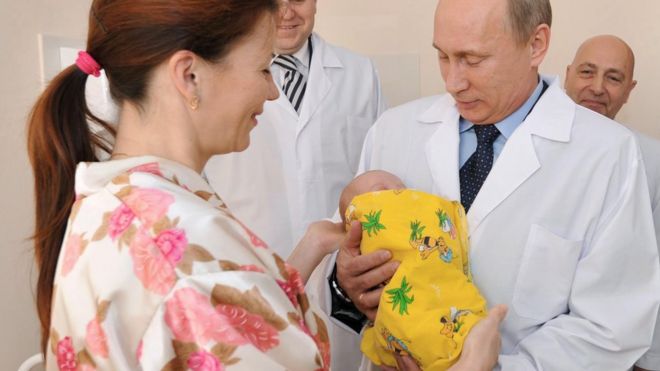 Владимир Путин держит ребенка во время поездки в больницу