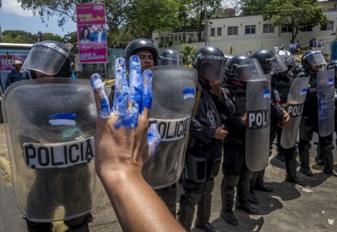Никарагуанские женщины протестуют перед полицией по охране общественного порядка во время демонстрации в Манагуа 2 мая 2018 года