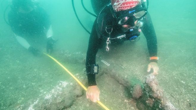 An underwater image of marine archaeologists take measurements of the anchors that date back to the 16th century