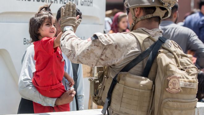 A U.S. Marine receives a high-five from a child during an evacuation at Hamid Karzai International Airport, Kabul, Afghanistan, August 21, 2021. Picture taken August 21, 2021