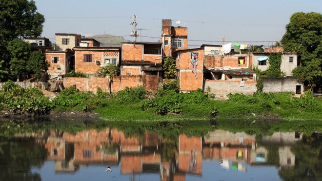 Casas precárias, sem pintura, na beira de canal poluído