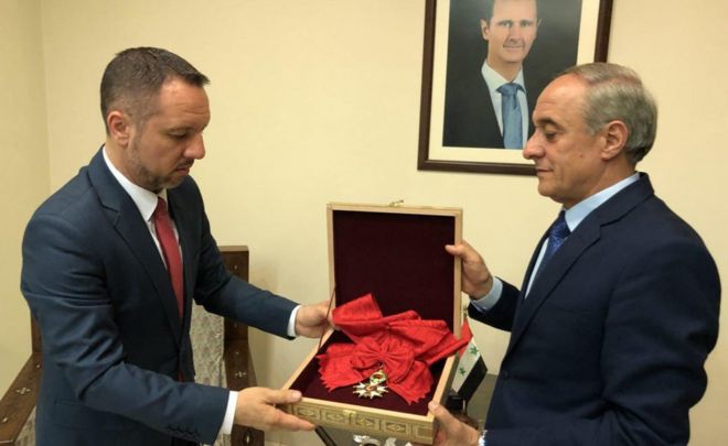 Снимок со страницы президента Сирии в Facebook показывает, что представитель иностранных дел Сирии вручает награду Legion d'honneur Grand Croix представителю посольства Румынии. 19 апреля 2018 года