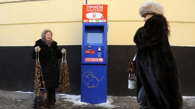 Пожилая женщина, продающая грибы на улице в Москве, а молодая женщина прогуливается по