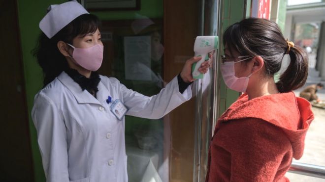 Медицинский работник измеряет температуру женщины