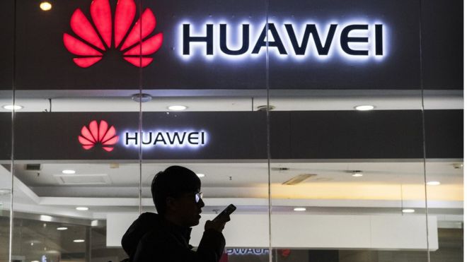 29 января 2019 года в Пекине, Китай, пешеход разговаривает по телефону, проходя мимо магазина Huawei Technologies Co.