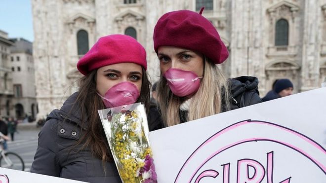 Two girls pose in Piazza Duomo holding signs dedicated to March 8th women"s day on March 08, 2020 in Milan, Italy