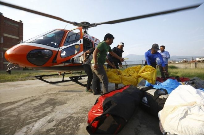 Чиновники несут тела индийских альпинистов, найденные на горе Эверест и доставленные по воздуху в Учебную больницу в Катманду 28 мая 2017 года.