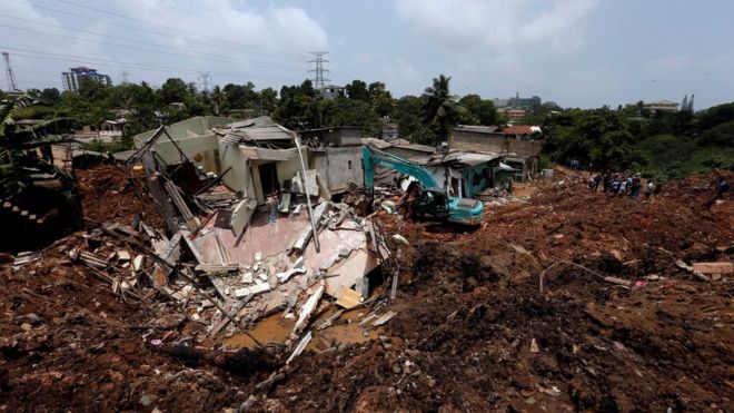 A bako machine works near damaged houses during a rescue mission after a garbage dump collapsed and buried dozens of houses in Colombo