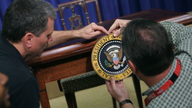 Рабочие прикрепляют президентскую печать США на столе в Белом доме