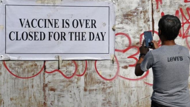 A man takes a photo of the notice stating ' Vaccine is over closed for the day' outside the gate of UNESCO vaccination center in Mumbai.