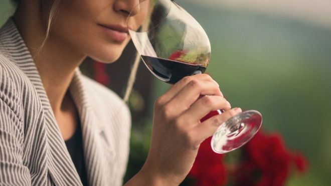 Женщина пьет стакан красного вина