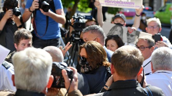 Американский актер Джонни Депп (C) жестом указывает на то, что он прибыл на десятый день судебного процесса по делу о клевете против News Group Newspapers (NGN) в Высоком суде Лондона, 20 июля 2020 г.