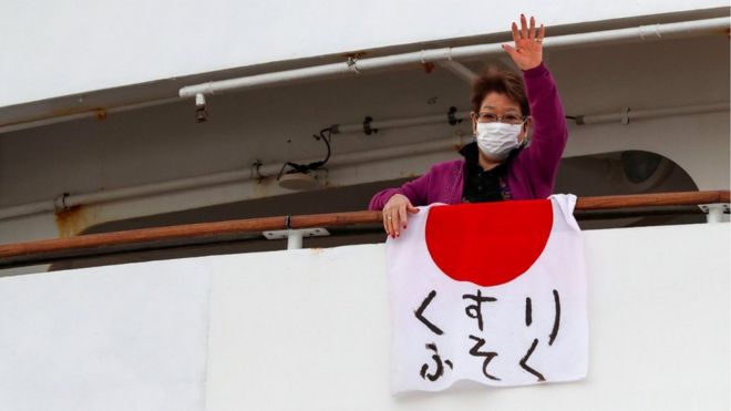 Pasajera del crucero Dream Princess exhibe una bandera japonesa en la que alerta sobre la falta de medicamentos.