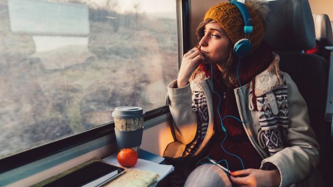 Молодая женщина слушает подкаст на поезде