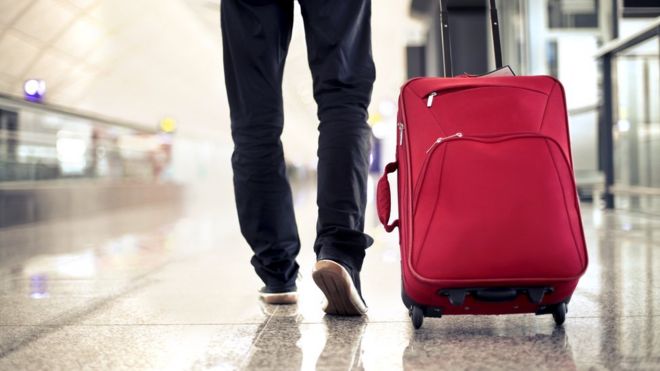 Man walking at an airport with a suitcase