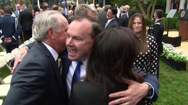 Mike Lee, centre, hugging other attendees at a Rose Garden event