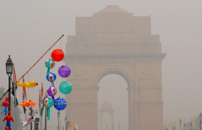 Надувные игрушки выставлены на продажу около Ворот Индии, которые видны погрязшими в смоге в Дели 5 ноября 2016 года.