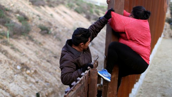 Мигранты из Гондураса, часть тысячелетнего каравана из Центральной Америки, пытающегося добраться до Соединенных Штатов, прыгают через пограничный забор, чтобы нелегально пересечь Мексику с США, в Тихуане, Мексика, 27 декабря 2018 года