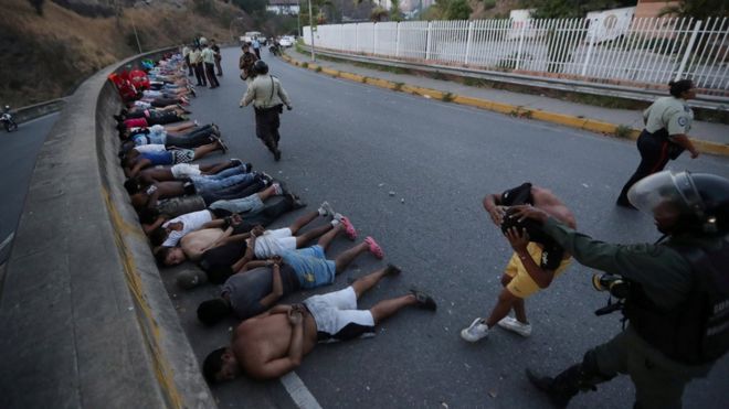 Люди, задержанные силами безопасности, лежат на улице после разграбления во время продолжающегося отключения электроэнергии в Каракасе, Венесуэла