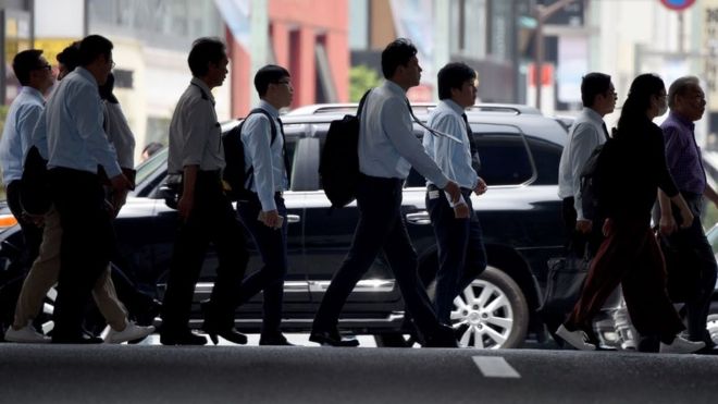 Офисные работники и пешеходы переходят улицу в Токио