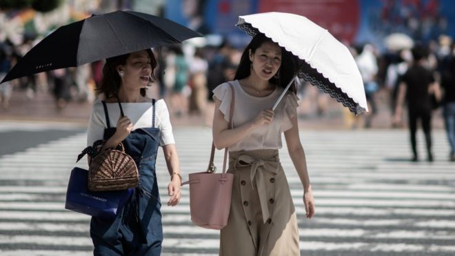 Žena nosi kišobran dok prelazi ulicu u Tokiju, 24. jul, 2018.