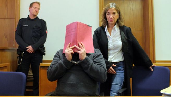 Niels Högel hides his face as he appears in court in November 2014