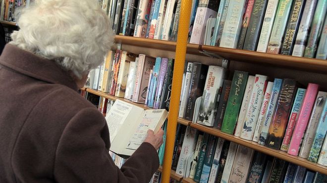 женщина читает книгу в библиотеке