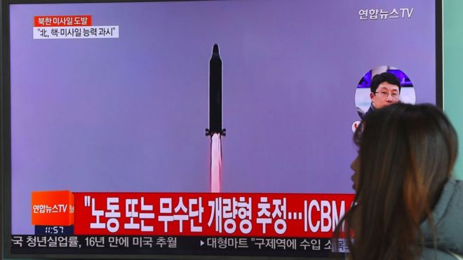 Женщина проходит мимо телевизионного экрана, показывающего файл с запуском ракеты Северной Кореи на железнодорожной станции в Сеуле