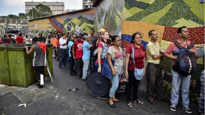 Люди стоят в очереди за барабанами для сбора воды и таблеток для очистки воды от членов Венесуэльского Красного Креста в окрестностях Катиа в Каракасе, Венесуэла, 16 апреля 2019 года.