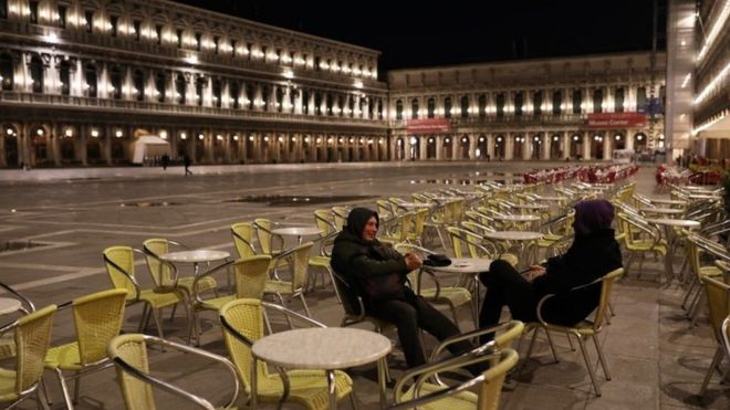Two people sit in a cafe on a virtually deserted San Marco Square in Venice, Italy. Photo: 8 March 2020