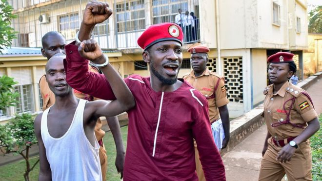 Opposition figurehead Hon Kagulanyi Robert aka Bobi Wine walks handcuffed together with another prisoner before boarding the prison bus leading him to Luzira maximum prison in Kampala on April 29, 2019. - Ugandan police arrested pop star turned MP Bobi Wine on April 29, barely two days after lifting the house arrest of a potential challenger to incumbent veteran President, and placed him in custody over a protest he organised last year, his lawyer said.